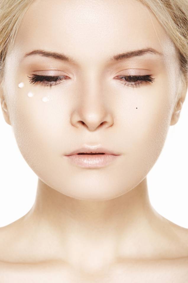Mulher com creme perto dos olhos Mulher com creme perto dos olhos