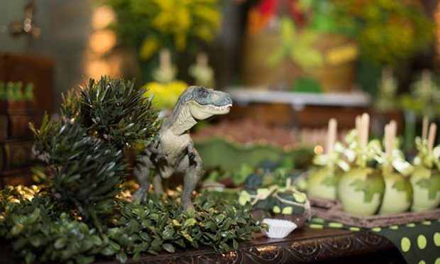 Dinossauro de brinquedo na mesa de doçes.