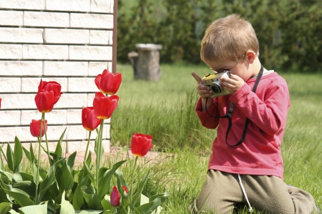 Criança tirando foto da flor