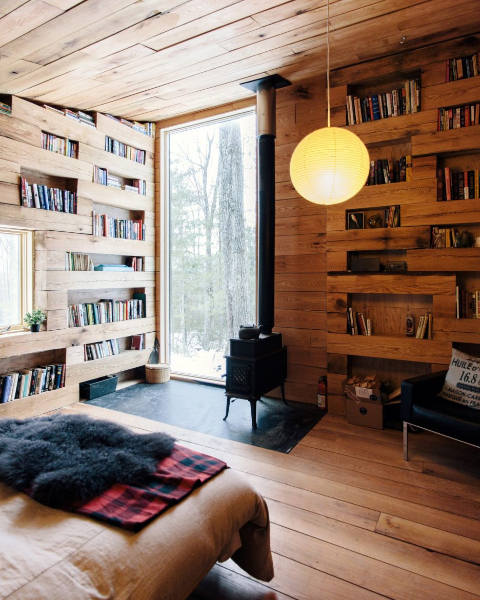 Inspiração do dia: cabana com biblioteca e lareira no meio da floresta