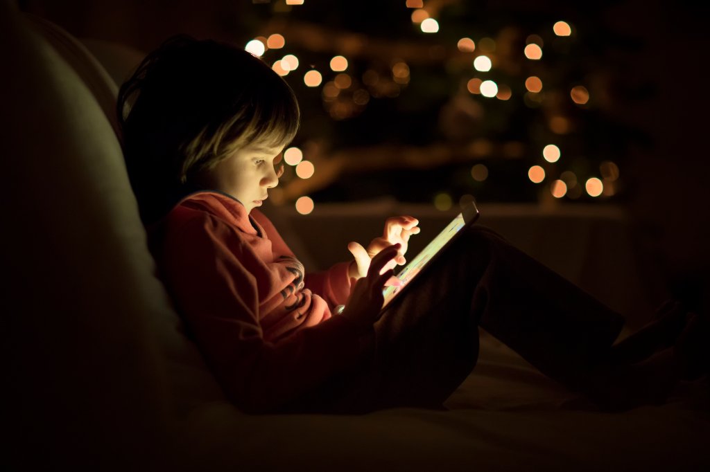 Criança usando tablet no escuro