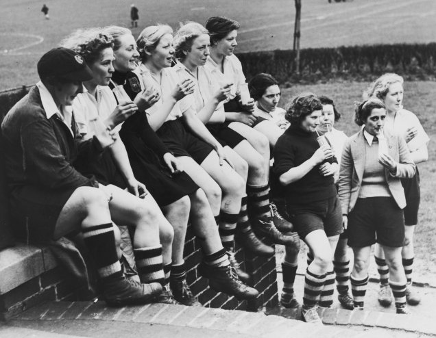 <span style="font-weight:400;">Durante seus anos de jogo, Preston Ladies quebrou uma série de barreiras. Tornou-se o primeiro time feminino a jogar uma partida internacional contra a equipe da França - evento que juntou mais de 25 mil espectadores - além de ter sido a primeira equipe a jogar sob os holofotes, na primeira partida noturna em 1920. Esta fotografia, de 1939, mostra a equipe durante o intervalo de um treino.</span>