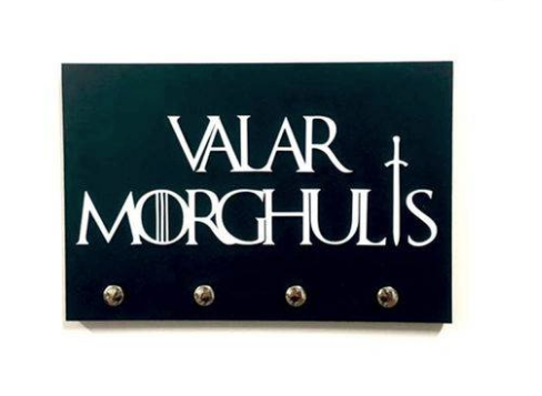 Porta-chave Valar Morghulis - Game of Thrones, de <span>MDF com acabamento em acrílico, tamanho 15 x 10 cm, com fita dupla-face para colar na parede</span>. <a href="https://www.americanas.com.br/produto/47776199/porta-chaves-valar-morghulis-game-of-thrones?WT.srch=1&acc=e789ea56094489dffd798f86ff51c7a9&epar=bp_pl_00_go_mv_todas_geral_gmv&gclid=EAIaIQobChMI5Jysq-Gi4QIVioeRCh0cFQADEAQYBiABEgK4IvD_BwE&i=5bce9123eec3dfb1f8a4d629&o=5c056856ebb19ac62cf65911&opn=YSMESP&sellerId=21881822000107" target="_blank" rel="noopener">Americanas</a>, R$ 62,91