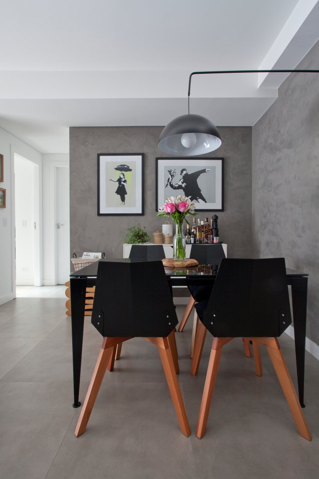 O clima moderno da sala da designer Priscila Kolberg vem do aspecto de concreto das paredes (uma textura que imita o acabamento) e do piso (de porcelanato). A mesa de metal preto é bem acompanhada pelas cadeiras Alpha. Na parede, serigrafias do grafiteiro Banksy.