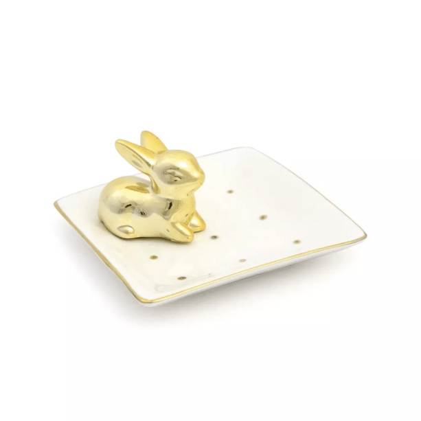 Prato com Coelho Dourado, de cerâmica (11 x 11 x 5 cm). <a href="https://www.artedolardecor.com.br/pascoa/Prato-com-Coelho-Detalhes-em-Dourado" target="_blank" rel="noopener">Arte do Lar</a>, R$ 65