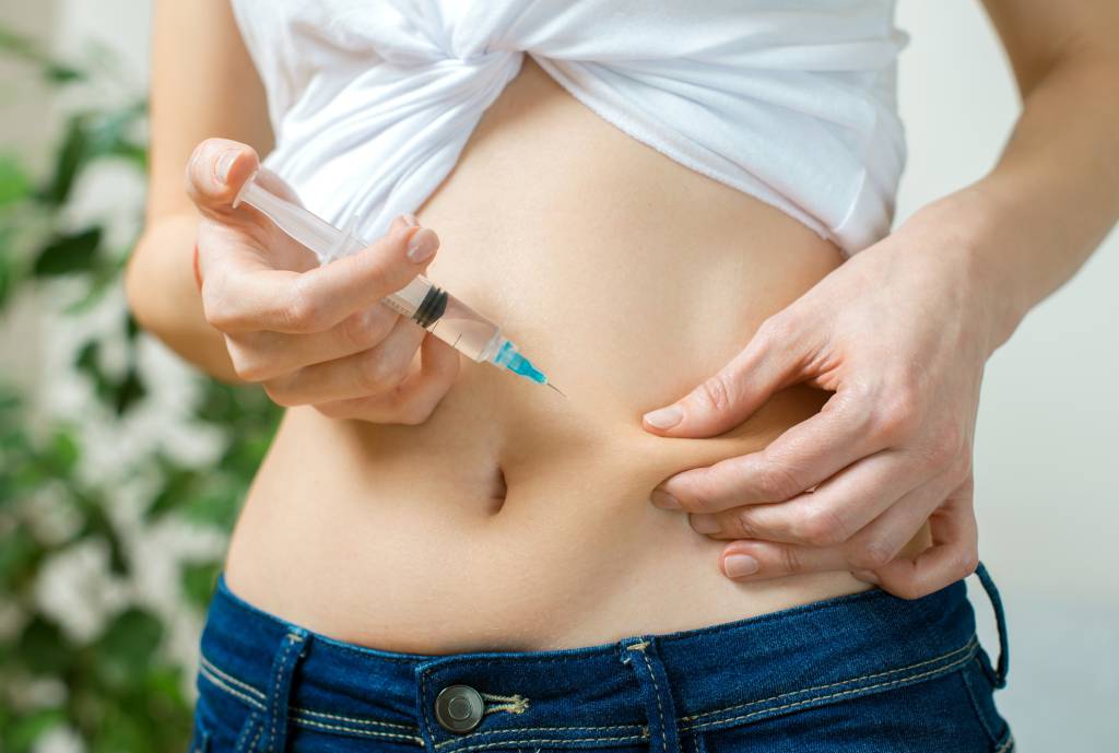 Woman giving herself insulin shot injection.