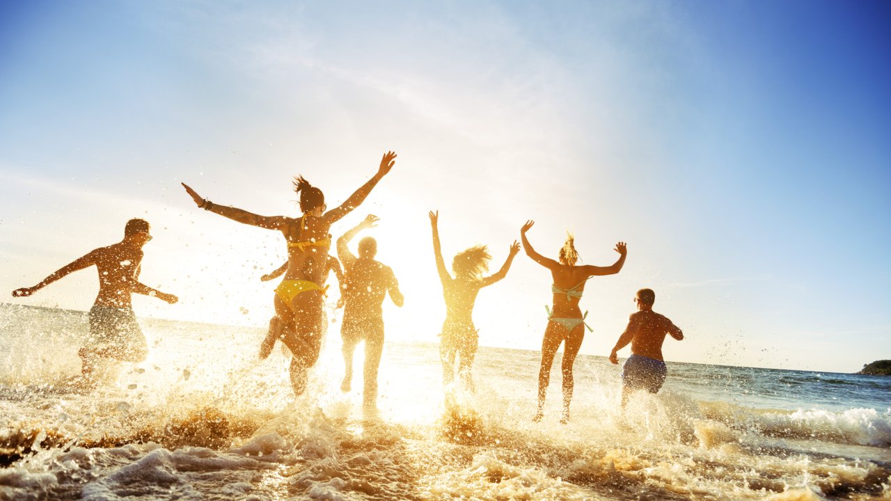 Crowd of people or friends runs to sunset sea. Beach holidays travel concept
