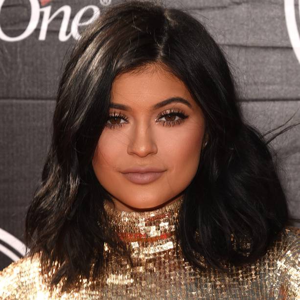 <strong>Kylie Jenner </strong>// Delineado a partir do meio da pálpebra, glitter dourado, cílios marcados e batom acinzentado.