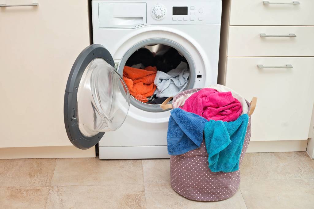 máquina de lavar roupa cheia Laundry basket in front of a washing machine