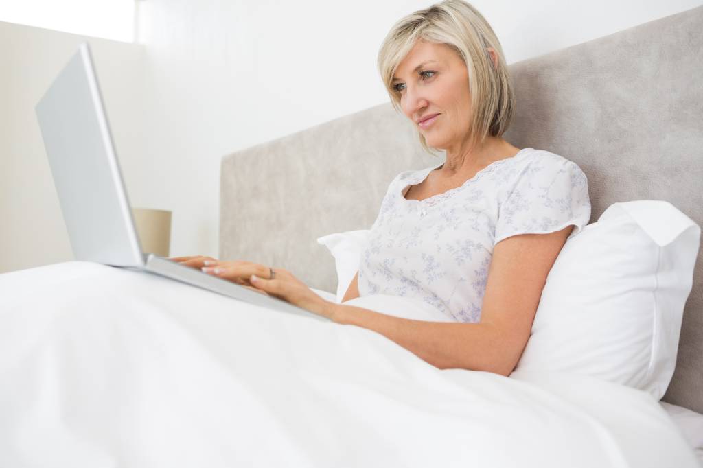 Woman using laptop in bed at home