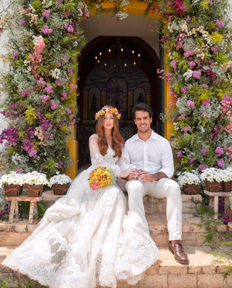 Um casal vestido com roupas de noiva e noivo estão sentados em um banco