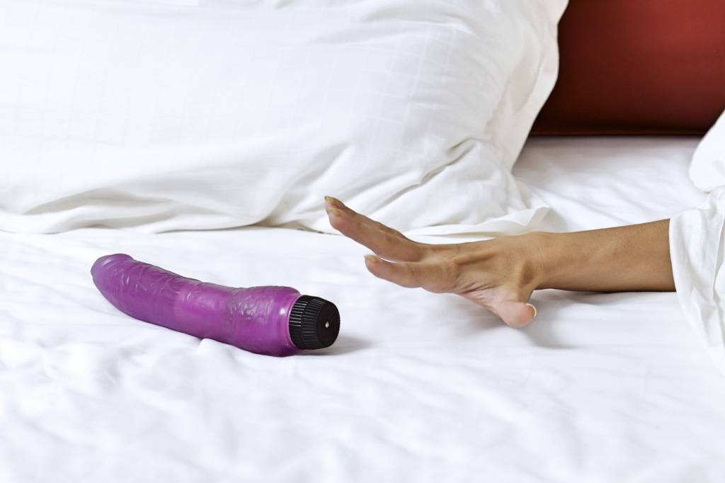 Woman’s hand reaching for dildo in bed