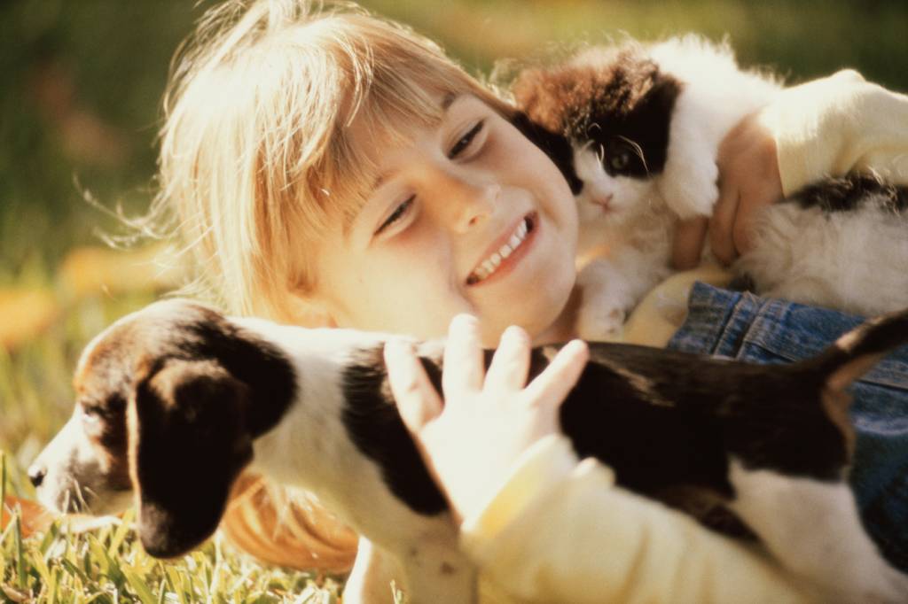 Menina segurando um cachorro e um gato