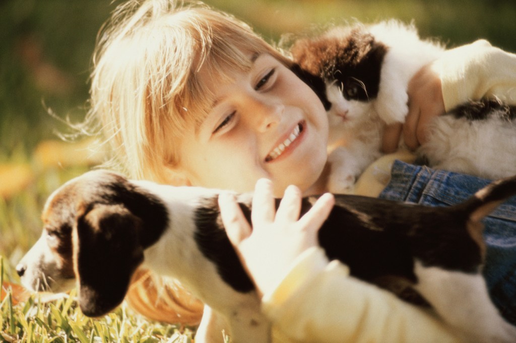 Menina segurando um cachorro e um gato