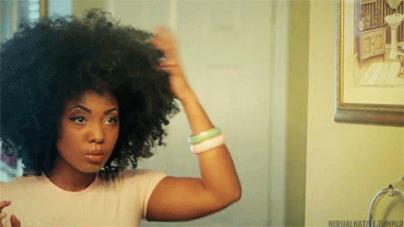 mulher negra se olhando no espelho e arrumando o cabelo