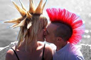 Casal de jovens punks se beijando durante festival na Inglaterra.