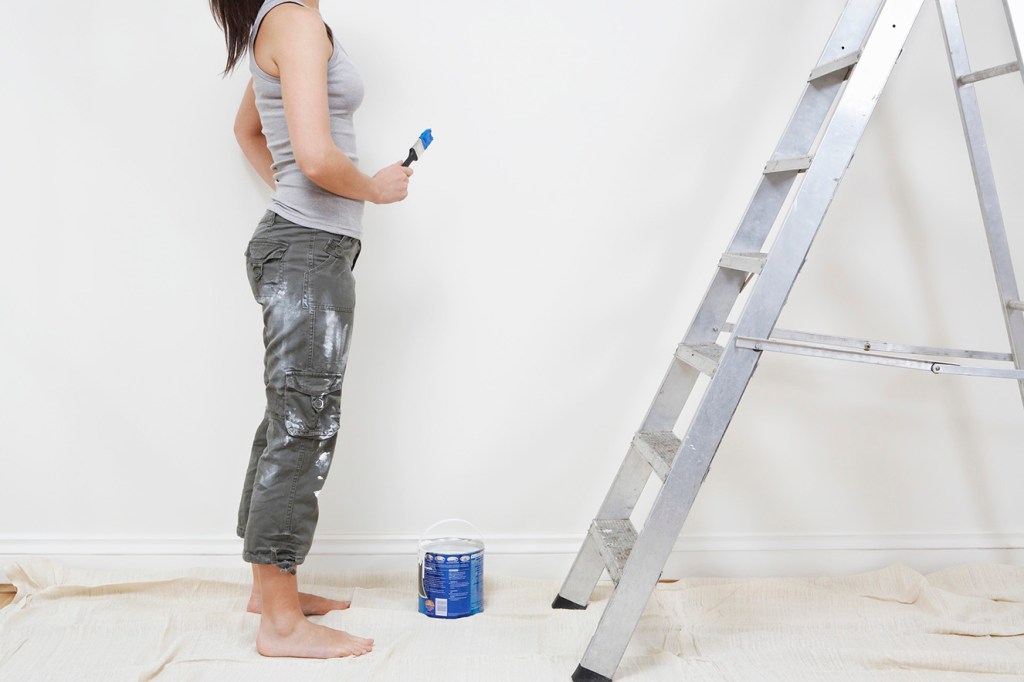 Mulher pintando a parede de casa durante reforma