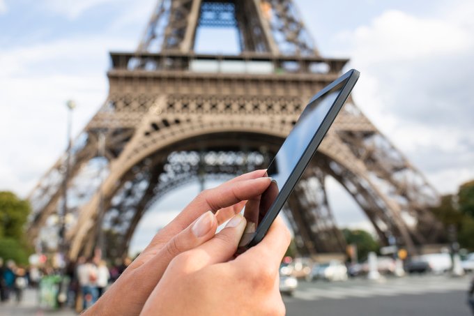 Woman using her smart phone in front of the Eiffel Tower