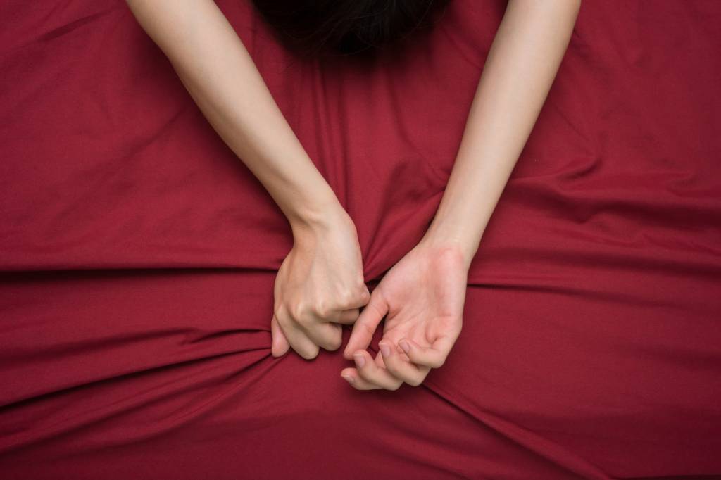 sexo hand grasping on bed sheet