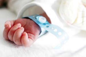 Mão de um recém-nascido com uma pulseira de identificação azul