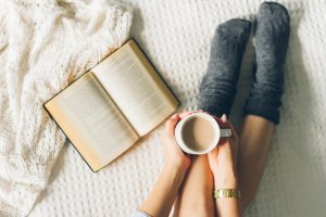 Mulher lendo livro e bebendo café com leite