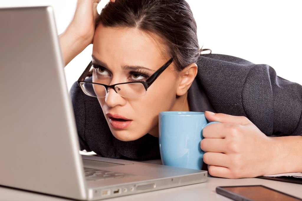 Sleepy and tired business woman on laptop, holding a coffee