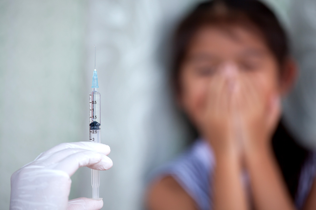 Close up doctor hand holding syringe with a child girl fear to receive vaccine injection background