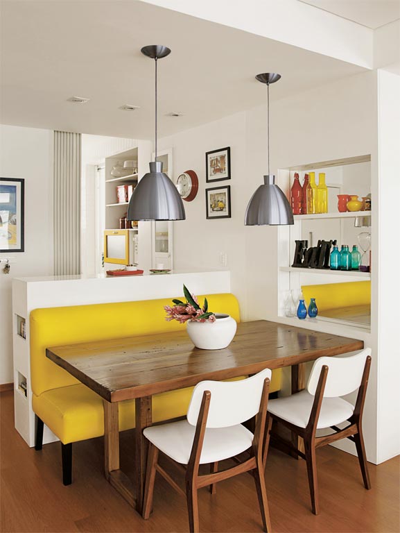 Na área de refeições, um sofá amarelo de couro sintético é o destaque da decoração. Uma mesa de cadeira maciça é servida por cadeiras, que acrescenta branco à combinação quente. Uma estante embutida, com fundo espelhado, amplia visualmente este canto. Projeto <span>das arquitetas Isabella Lucena e Joanna Fraga.</span> Na área de refeições, um sofá amarelo de couro sintético é o destaque da decoração. Uma mesa de cadeira maciça é servida por cadeiras, que acrescenta branco à combinação quente. Uma estante embutida, com fundo espelhado, amplia visualmente este canto. Projeto <span>das arquitetas Isabella Lucena e Joanna Fraga.</span>