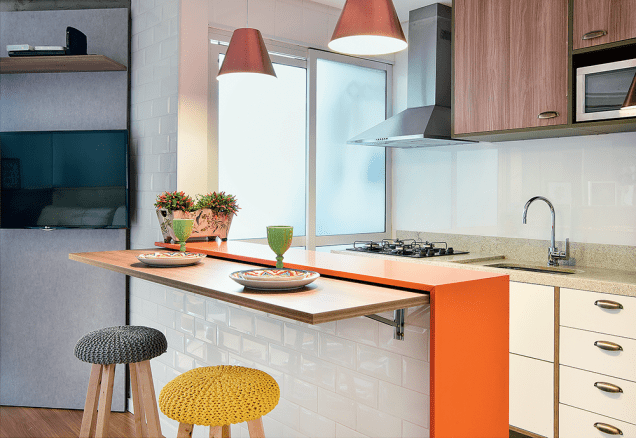 <span>A bancada laranja (quartzo Naranja, da Empório Stone. Marmoraria Pedra Julia</span><span>) é o chamariz da cozinha de 9 m², projeto dos arquitetos Daniele Capo, Bruna Turquiai e Italo Priore, do IBD. “Todo o restante foi pensando para compor com ela”, diz Daniele. É o caso do amadeirado da porta do armário suspenso e da mesa retrátil, que, com o gabinete da pia, completam a marcenaria (Edy Planejados). A parede da pia foi revestida com vidro leitoso (Adelos Vidros), que permite anotações</span>