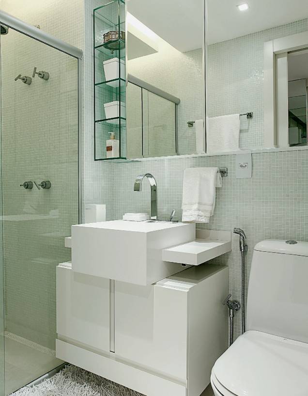Com apenas 3 m², o banheiro íntimo foi vestido inteiramente de branco, medida que evitou a sensação de clausura e ainda deu à área uma atmosfera elegante. O projeto de estilo clean soma pastilhas de vidro, bancada de silestone e mobiliário sob medida. “Projetamos o gabinete inferior menos profundo do que a cuba para criar a ideia de movimento. Essa é uma ótima pedida para ambientes pequenos”,justifica o arquiteto. Mais fininho ainda (com apenas 12 cm de profundidade), o armário suspenso é revestido de espelhos e ladeado por prateleiras de vidro, que, com sua transparência, contribuem para a fluidez da ambientação. Projeto d<span>o arquiteto paulista </span><span>Thiago Manarelli</span><span> e da designer de interiores pernambucana </span><span>Ana Paula Guimarães.</span> Com apenas 3 m², o banheiro íntimo foi vestido inteiramente de branco, medida que evitou a sensação de clausura e ainda deu à área uma atmosfera elegante. O projeto de estilo clean soma pastilhas de vidro, bancada de silestone e mobiliário sob medida. “Projetamos o gabinete inferior menos profundo do que a cuba para criar a ideia de movimento. Essa é uma ótima pedida para ambientes pequenos”,justifica o arquiteto. Mais fininho ainda (com apenas 12 cm de profundidade), o armário suspenso é revestido de espelhos e ladeado por prateleiras de vidro, que, com sua transparência, contribuem para a fluidez da ambientação. Projeto d<span>o arquiteto paulista </span><span>Thiago Manarelli</span><span> e da designer de interiores pernambucana </span><span>Ana Paula Guimarães.</span>