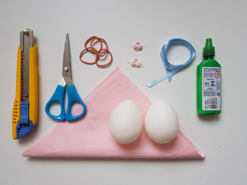 Material: Ovos de plástico, ovos galinha ou pata ou de isopor, guardanapos de tecido ou papel, estilete, lixa, elástico de borracha, fita de cetim azul claro 7mm (ou outra cor) e focinhos de coelho.