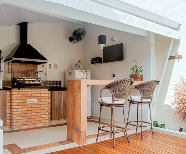 <span>Repaginada, a churrasqueira virou um verdadeiro espaço gourmet, com cooktop, geladeira, marcenaria sob medida, TV balcão e banquetas. Um toldo de lona prolonga a área coberta.</span> <span>Repaginada, a churrasqueira virou um verdadeiro espaço gourmet, com cooktop, geladeira, marcenaria sob medida, TV balcão e banquetas. Um toldo de lona prolonga a área coberta.</span>