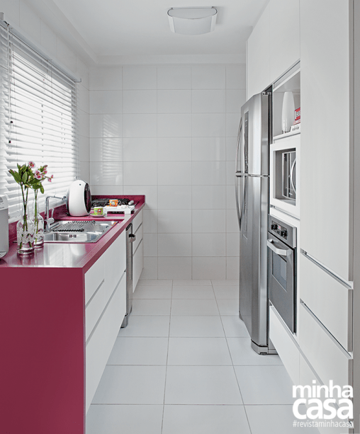 A bancada de Silestone em tom de magenta e dá vida ao ambiente branco desta linda cozinha. Projeto da <span>arquiteta Andréia Karalkovas.</span>