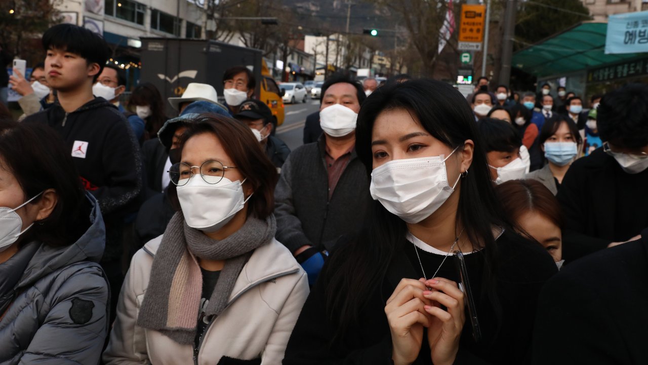Sul-coreanos vestindo máscaras enquanto ouvem o discurso do parlamentar Lee Nak-yon