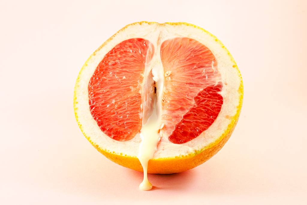 Sexy grapefruit with sperm, erotic concept. Sectional grapefruit is a symbol of the vagina and clitoris. Half grapefruit with dripping white liquid on a pastel background. Erotic concept. Sexy grapefruit with sperm, erotic concept. Sectional grapefruit is a symbol of the vagina and clitoris. Half grapefruit with dripping white liquid on a pastel background. Erotic concept.