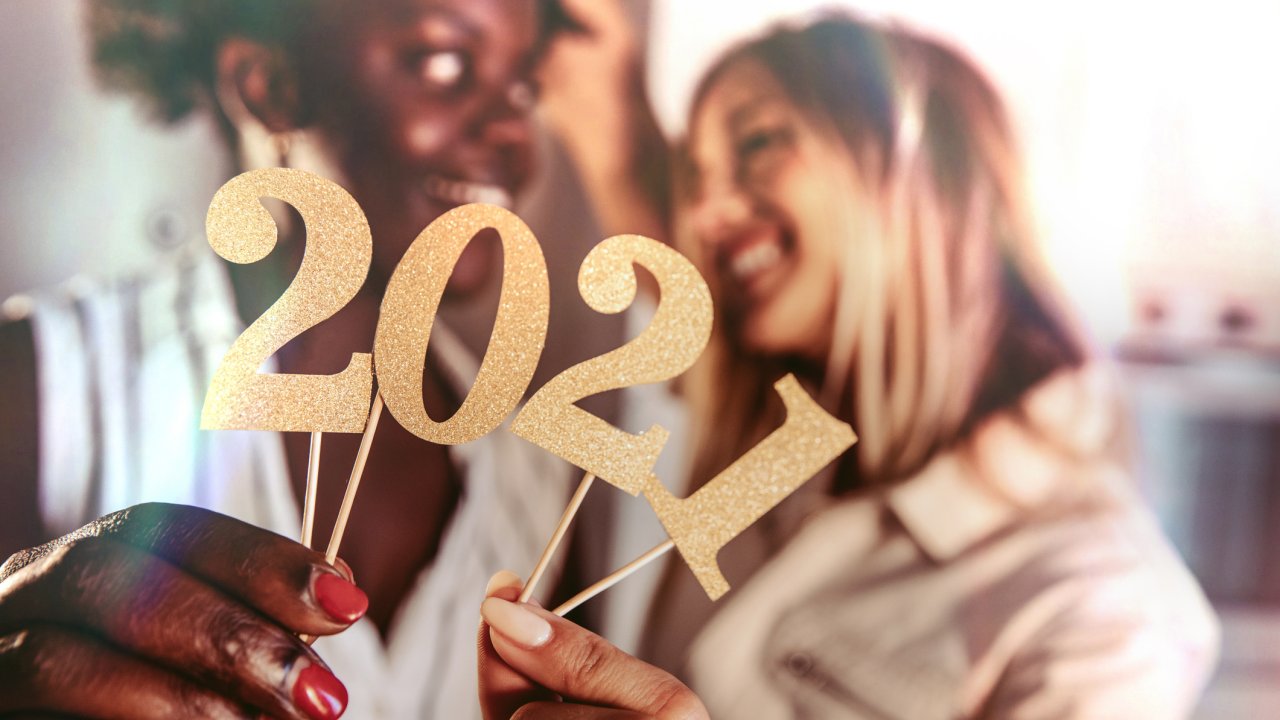Mulheres celebrando o ano novo segurando enfeites com os algarismos 2021