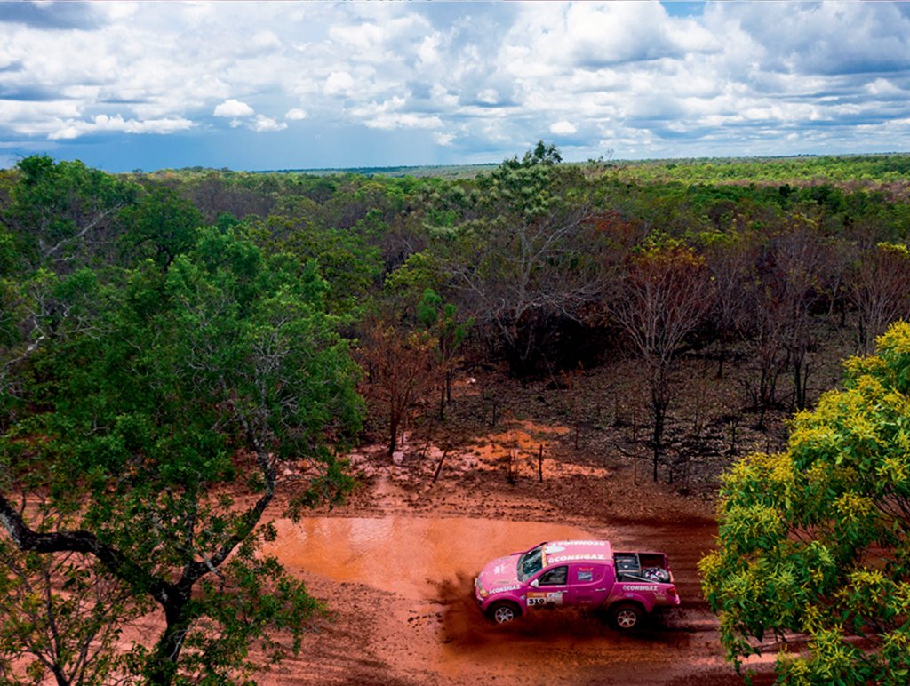 Numa pista lamacenta cercada por árvores surge uma caminhonete pink