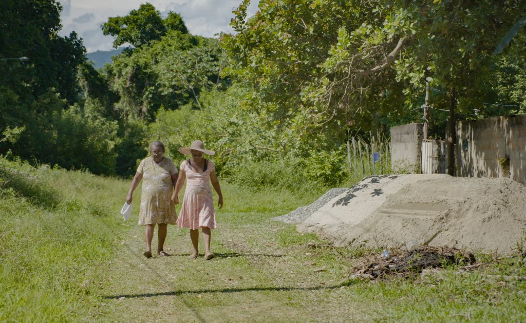 mulheres caminham de mãos dadas numa área rural