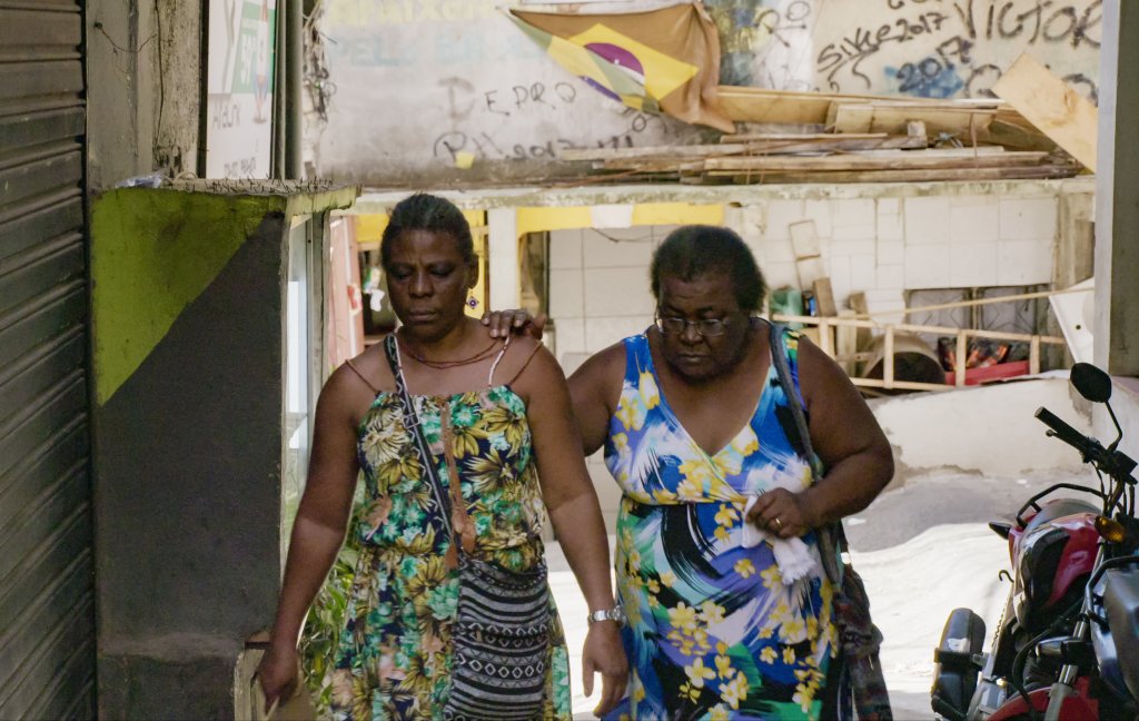 Casal de mulheres caminha pela rua com uma se apoiando na outra