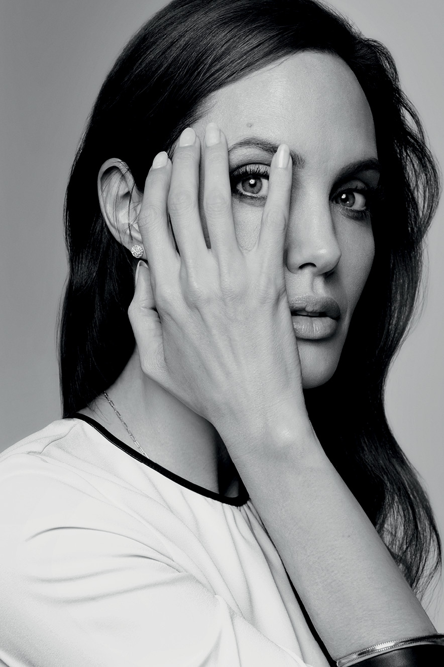 Angelina Jolie com a mão no rosto permitindo ver seu olho por entre seus dedos