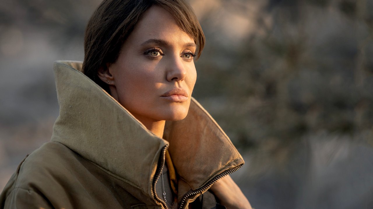 Angelina Jolie olha para o horizonte usando um grande casaco