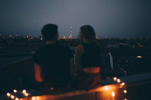 Rear view of couple sitting on terrace against cityscape at dusk