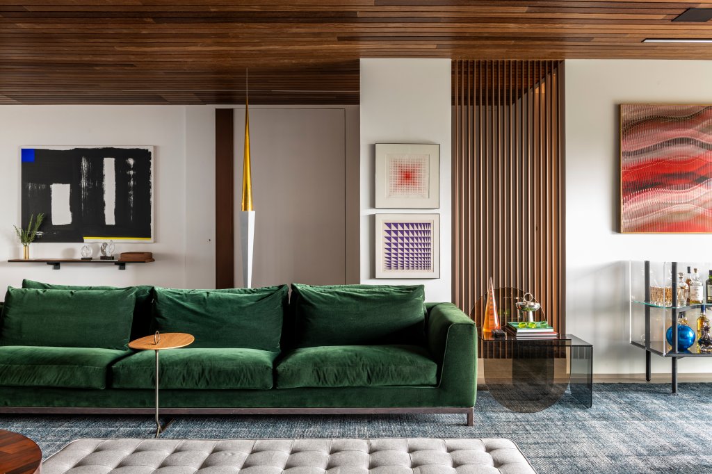 Sala de estar com madeira, sofá verde e quadros na parede