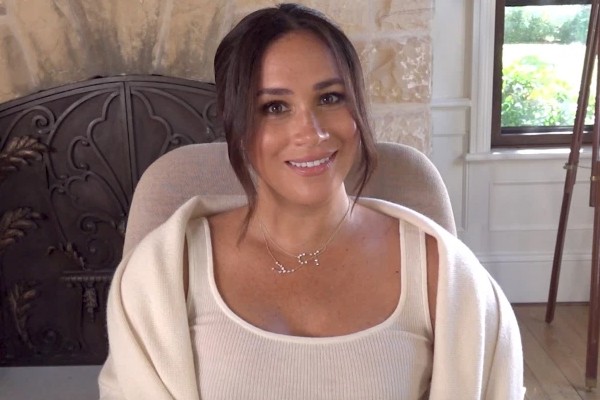 Meghan Make de branco com cabelo preso e colar brilhante.