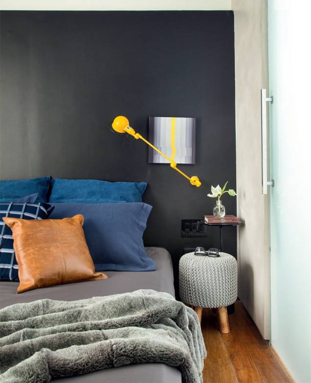 Os arquitetos Rodrigo Beze e Carlos Carvalho, do Studio Ro+Ca, escolheram o preto acetinado para a parede da cabeceira neste quarto. Os travesseiros em tons de azul e de couro, além do quadro que cria uma composição com a luminária amarela, dão o tom descolado da suíte. Os arquitetos Rodrigo Beze e Carlos Carvalho, do Studio Ro+Ca, escolheram o preto acetinado para a parede da cabeceira neste quarto. Os travesseiros em tons de azul e de couro, além do quadro que cria uma composição com a luminária amarela, dão o tom descolado da suíte.