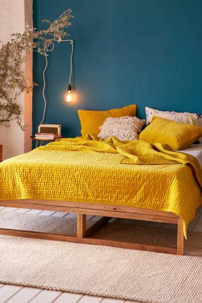 A dupla verde e amarelo ficou sofisticada no décor deste quarto, com o tom petróleo da parede de destaque e o mostarda da roupa de cama.