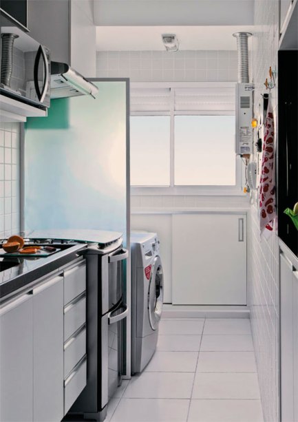 A cozinha e a lavanderia contam com os mesmos revestimentos e a separação entre elas é sutil: uma divisória opaca colocada entre o fogão e a máquina de lavar. A cozinha e a lavanderia contam com os mesmos revestimentos e a separação entre elas é sutil: uma divisória opaca colocada entre o fogão e a máquina de lavar.