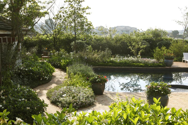 PAISAGISMO - O jardim planejado por Claudia D’Ávila segue os preceitos do Feng Shui. O lago com carpas e uma pequena queda d’água favorecem a prosperidade, a saúde e a harmonia. O terreno foi nivelado e um caminho com suaves curvas permitem que os usuários, principalmente o cadeirante da casa, possam acessar todos os recantos do jardim, que exibem diferentes cores, texturas e perfumes o ano todo.