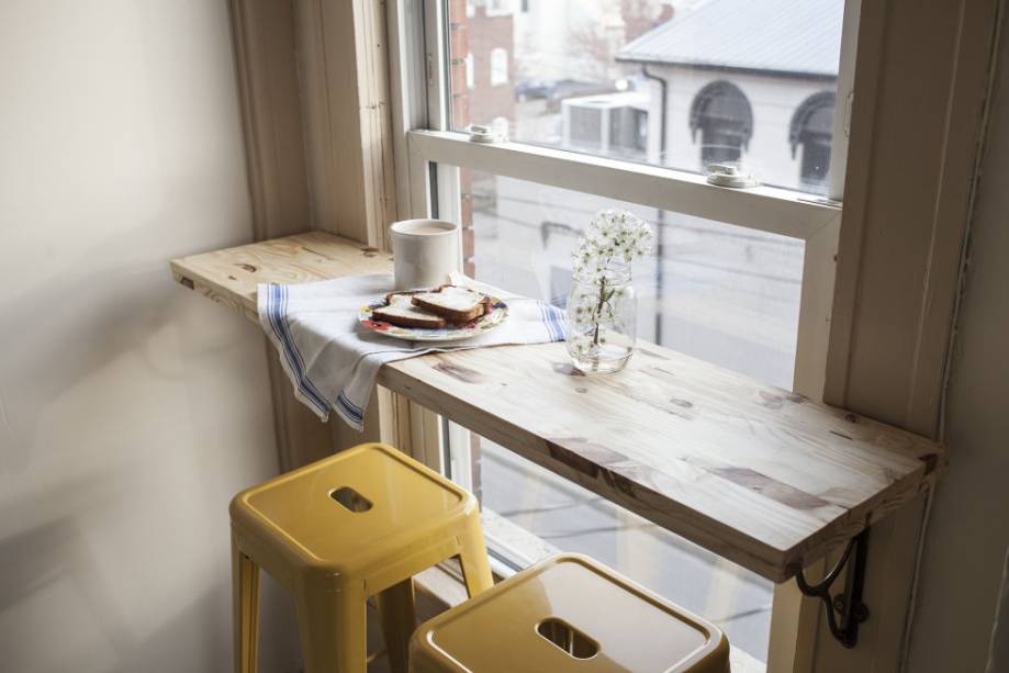 A bancada instalada na janela com mãos francesas substituiu a mesa de jantar quando a moradora se mudou de uma casa para um apartamento pequeno. As banquetas amarelas finalizam o cantinho para café da manhã com vista para a rua.