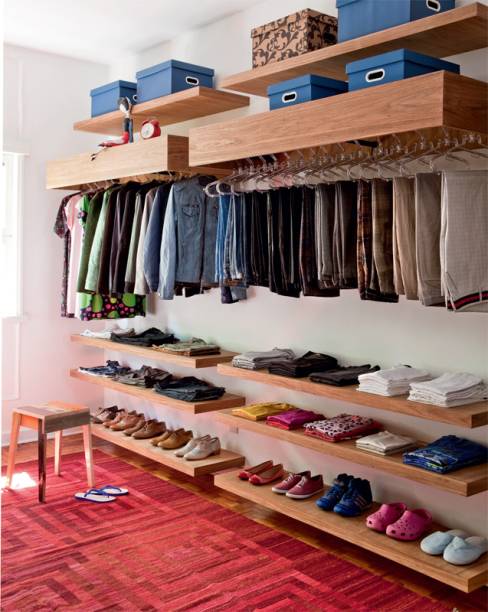 Executado pela Dogi Marcenaria, o closet de 10 m² tem prateleiras de freijó natural sarrafeado chumbadas nas paredes. As estruturas que ocultam os varões para cabides são fechadas no topo e oferecem espaço para caixas organizadoras (Kalunga), nas quais ficam as roupas menos usadas.